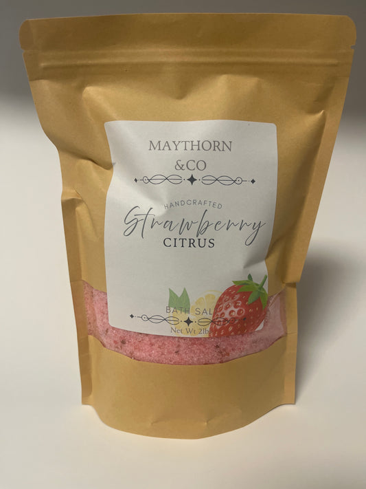 Maythorn & Co Strawberry Citrus Bath Salt in a clear jar with pink and orange bath salts, fresh strawberries, and citrus slices inside.