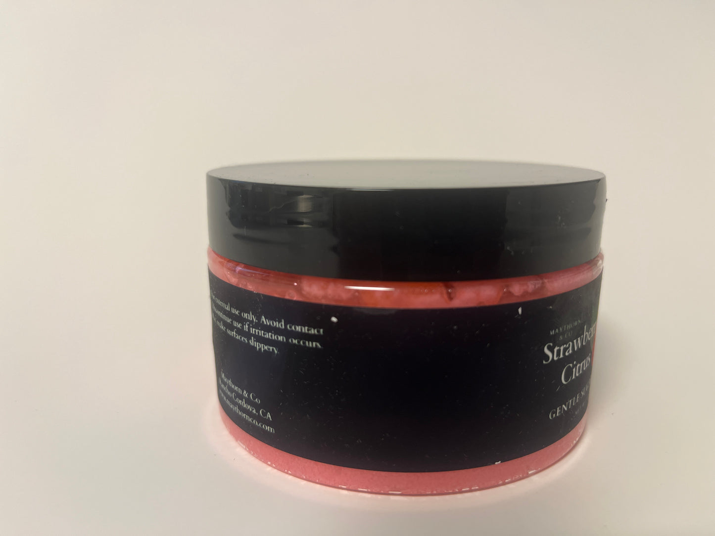 Maythorn & Co Strawberry Citrus Body Scrub featuring fresh strawberries and citrus slices in a jar with textured scrub texture.