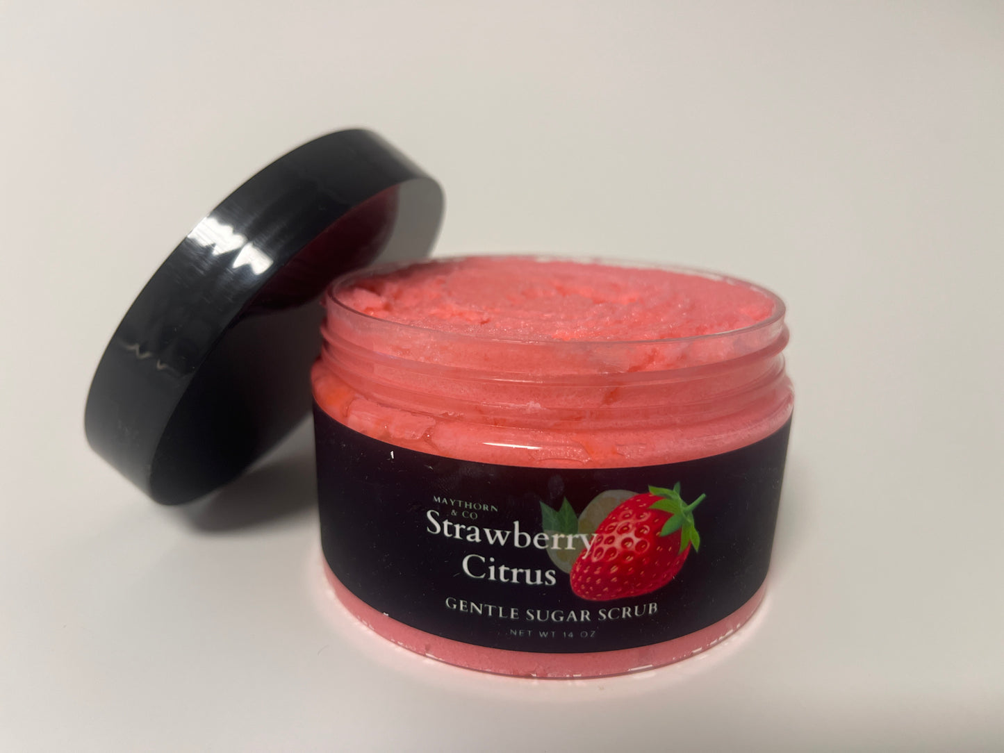 Maythorn & Co Strawberry Citrus Body Scrub jar with textured scrub and fresh strawberry and citrus slices visible inside.