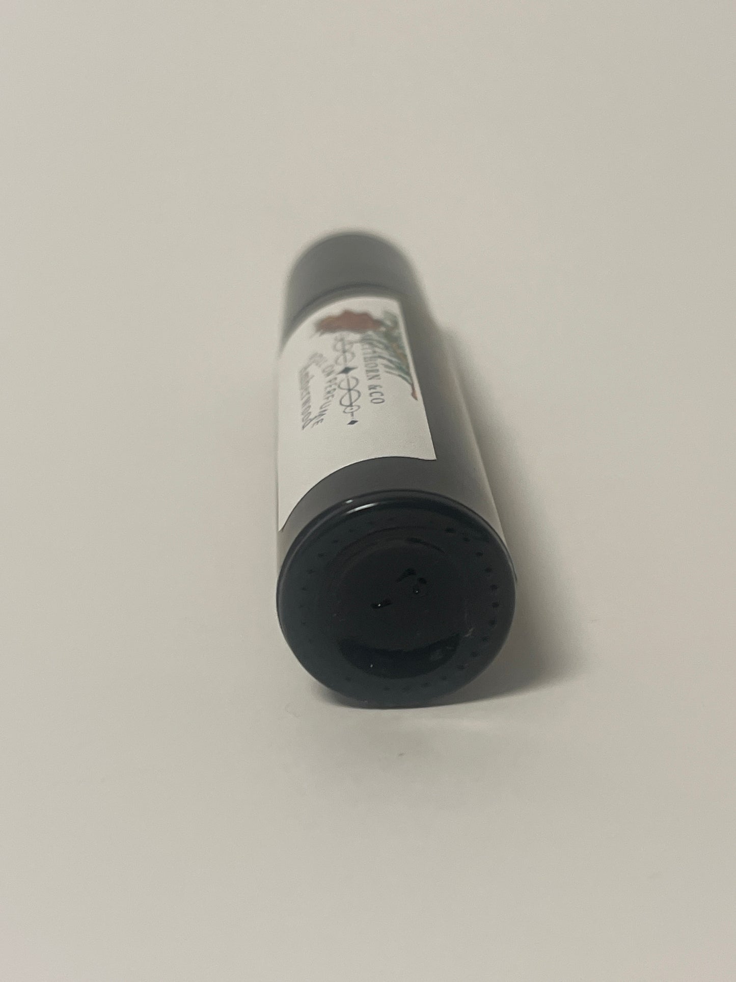 Amberwood roll-on perfume by Maythorn & Co featuring a sleek glass bottle with a black roll-on applicator.