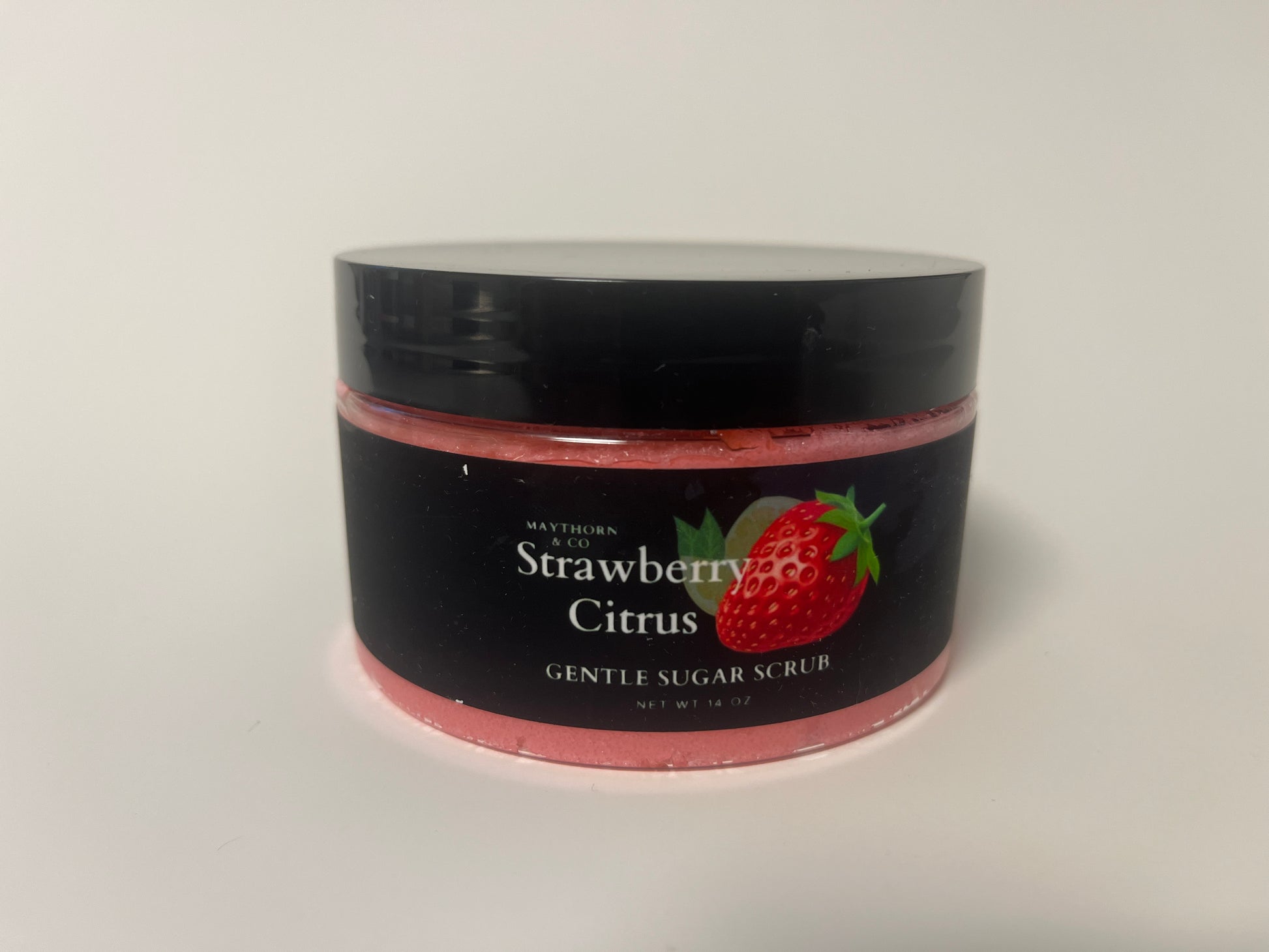Maythorn & Co Strawberry Citrus Body Scrub with fresh strawberries and citrus slices in a jar, ready for skincare.